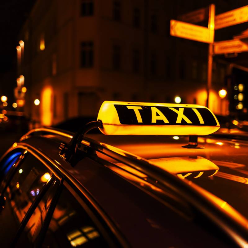 taxi sign on the roof of a taxi at night